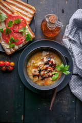 Homemade pea soup with chicken, vegetables and parsley, toast with red tomatoes and spices. Top view. Vertical shot