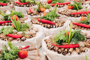 Side view of vegetables served on table during picnic. Tasty rolls with filling, red pepper and parsley. Healthy food lying on buffet table. Concept of dish, meal and culinary.