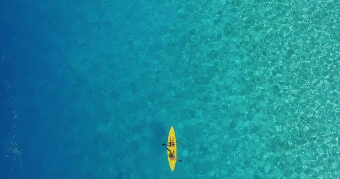 Aerial view of couple tandem kayaking together in deep blue and turquoise ocean water, perfect ocean kayaking in lagoon paradise
