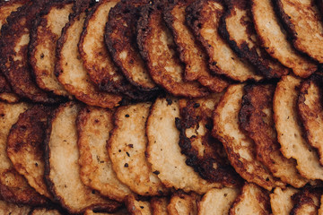 Close-up of delicious fried potato pancakes in stainless container outdoors. Food festival concept.