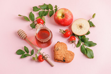 Ingredinets for winter fall autumn seasonal beverage tea party - fresh rose hip berries, honey, apple and heart-shaped biscuits. Concept of cozy teaparty witn immunity drink