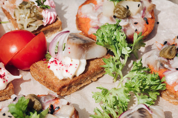 Macro of delicious canape or sandwiches with fresh herring, black sesame, cream cheese on crispy bread.
