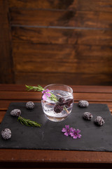 gin and tonic with blackberries, a sprig of rosemary and a flower of ornament