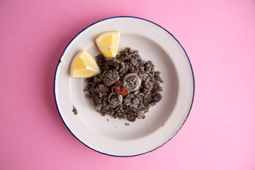 Plate of black rice with squid and prawns or Valencian black paella