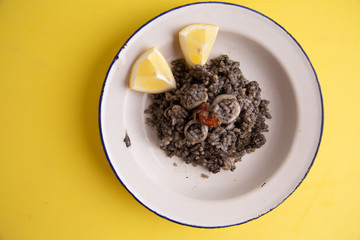 Plate of black rice with squid and prawns or Valencian black paella