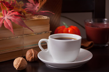 Cup of coffee, autumn leaves, pumpkin, books on the wooden table. Autumn harvest. Autumn concept.
