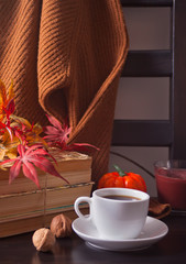 Cup of coffee, autumn leaves, pumpkin, books and sweater on the wooden chair. Autumn concept.