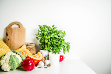 Autumn dinner cooking ingredients, various raw organic vegetables and greens on white kitchen table, copy space