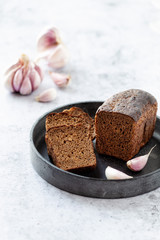 Loaf of rye bread with garlicon a black stone tray