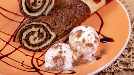 Chocolate rolls and ice cream balls, sprinkled with chocolate chips on a plate