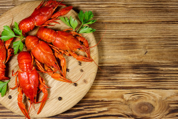 Boiled crayfish on cutting board on wooden table. Top view