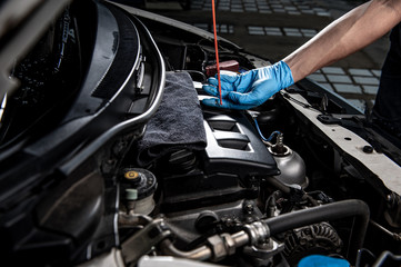 Hand of auto mechanic checking car engine at the repair garage