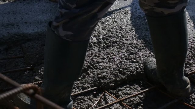Builder With Rubber Boots Filling Wet Concrete Out Of High Pressure Hydraulic Cement Pump Rubber Hose.