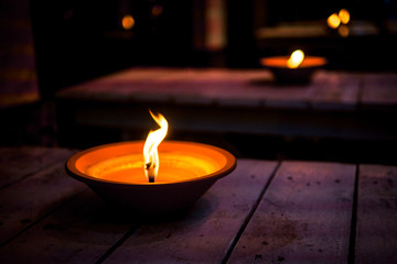 Oil lamps flaming at night on the wooden tables, close up. Romantic restarurant exterior.