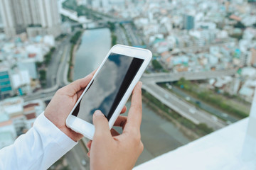 Woman uses Mobile Phone at cityscape background in morning light, close up