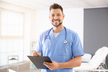 Male nurse with stethoscope and clipboard in clinic - obrazy, fototapety, plakaty