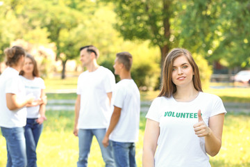 Fototapeta na wymiar Portrait of female volunteer showing thumb-up outdoors
