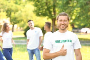 Portrait of male volunteer showing thumb-up outdoors