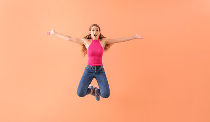 Beautiful jumping young woman on color background