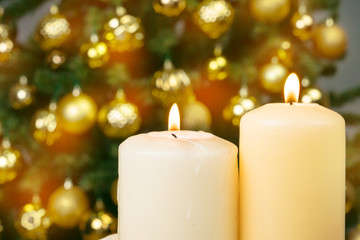 Obraz na płótnie Canvas Lit christmas candle against decorated fur tree background