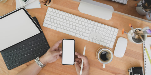 Top view of professional designer looking for idea on smartphone on wooden table