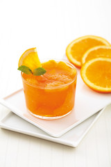 Orange juice in a glass and three piece of orange on white plate and background.
