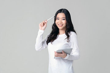 Smiling Asian woman holding tablet and stylus pen in thinking gesture