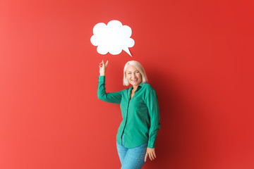 Mature woman with blank speech bubble on color background