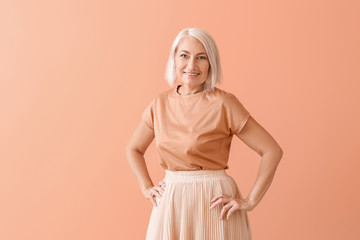 Stylish mature woman on color background