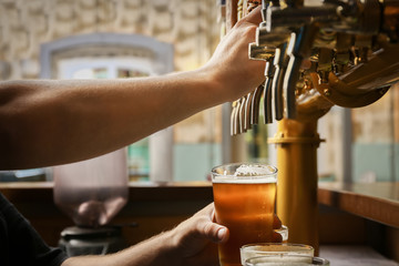 Fototapeta na wymiar Barman pouring fresh beer in glass, closeup