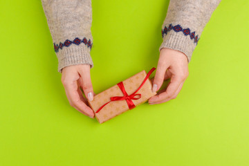 Woman hands holding gift box on green background