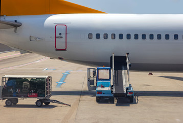 Loading - unloading bags, luggage and to/from an airplane in the airport. Cargo on vehicle waits for transport to airplane.