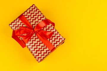 Decorated colored present on yellow background flatlay