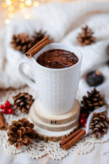 Cup of hot chocolate served in a white mug on a knitted vintage napkin. Delicious sweet dessert, rustic style. Cozy and warm holiday atmosphere, natural ingredients for festive mood