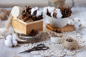 Obraz na płótnie Canvas Family time to wrap christmas presents! Ideas for hand made gifts decoration in rustic style, natural ingredients, cozy mood. Wooden background, scissors, rope, lace, cones, cinnamon and cotton