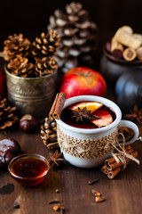 Obraz na płótnie Canvas Cozy time at home with a metal mug of hot mulled wine. Autumn, warm clothes, natural ingredients, spice, fruit and honey. Corkscrew to open wine. Rustic decor, festive mood