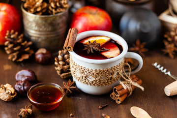 Cozy time at home with a metal mug of hot mulled wine. Autumn, warm clothes, natural ingredients, spice, fruit and honey. Corkscrew to open wine. Rustic decor, festive mood