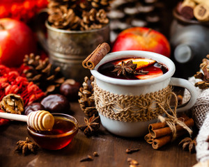 Obraz na płótnie Canvas Cozy time at home with a metal mug of hot mulled wine. Autumn, warm clothes, natural ingredients, spice, fruit and honey. Corkscrew to open wine. Rustic decor, festive mood