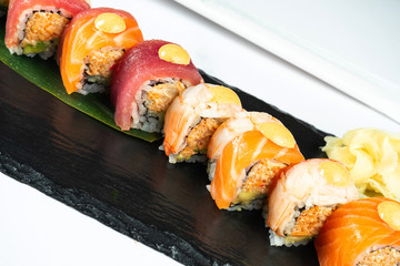 Set sushi rolls served on a banana leaf on a black stone on a marble table with chopsticks and soy sauce. Japanese food. Salmon and Tuna Shrimp Sushi. Healthy seafood. Food photo