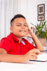 Fototapeta premium Portrait of the schoolboy siting at the table indoors and doing their homework