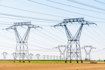 Dozens of electricity pylons in the french countryside under a clear blue sky.