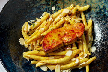 Unusual homemade Italian pasta with foie gras liver in a stylish black bowl on a marble background. Food photo background. Italian cuisine. © ismishko