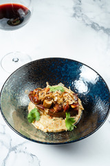Tasty Beef tongue steak with mushrooms served on mashed vegetables in a stylish black bowl on a marble background. Food photo background for menu or recipe