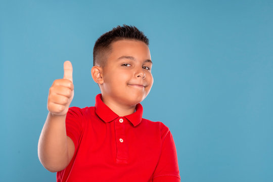 Studio shot of a young boy  civing you an approving gesture, isolated on blue  with copy space