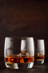 A glass of whiskey with ice on a wooden table