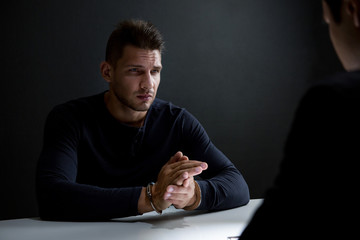 Criminal man with handcuffs in interrogation room