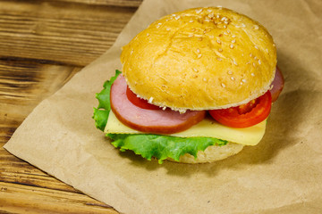 Fresh delicious homemade cheeseburger on brown paper on wooden table