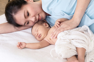 Asian beautiful mother hug adorable newborn baby 0-1 month sleep with comfortable safe in bed together at home