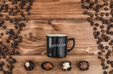 Side of black cup and beans and sweets with title espresso on the brown wooden table