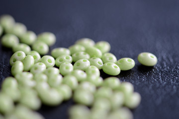 Twin beads light green color scattered on a dark surface close up